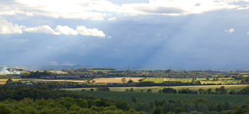 Gods rays in front of storm clouds over spring fields.jpg